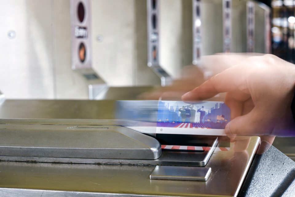 A photo of a human hand swiping a MetroCard at a New York City subway stations.