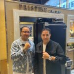 Two men pose in front of a jewelry store.