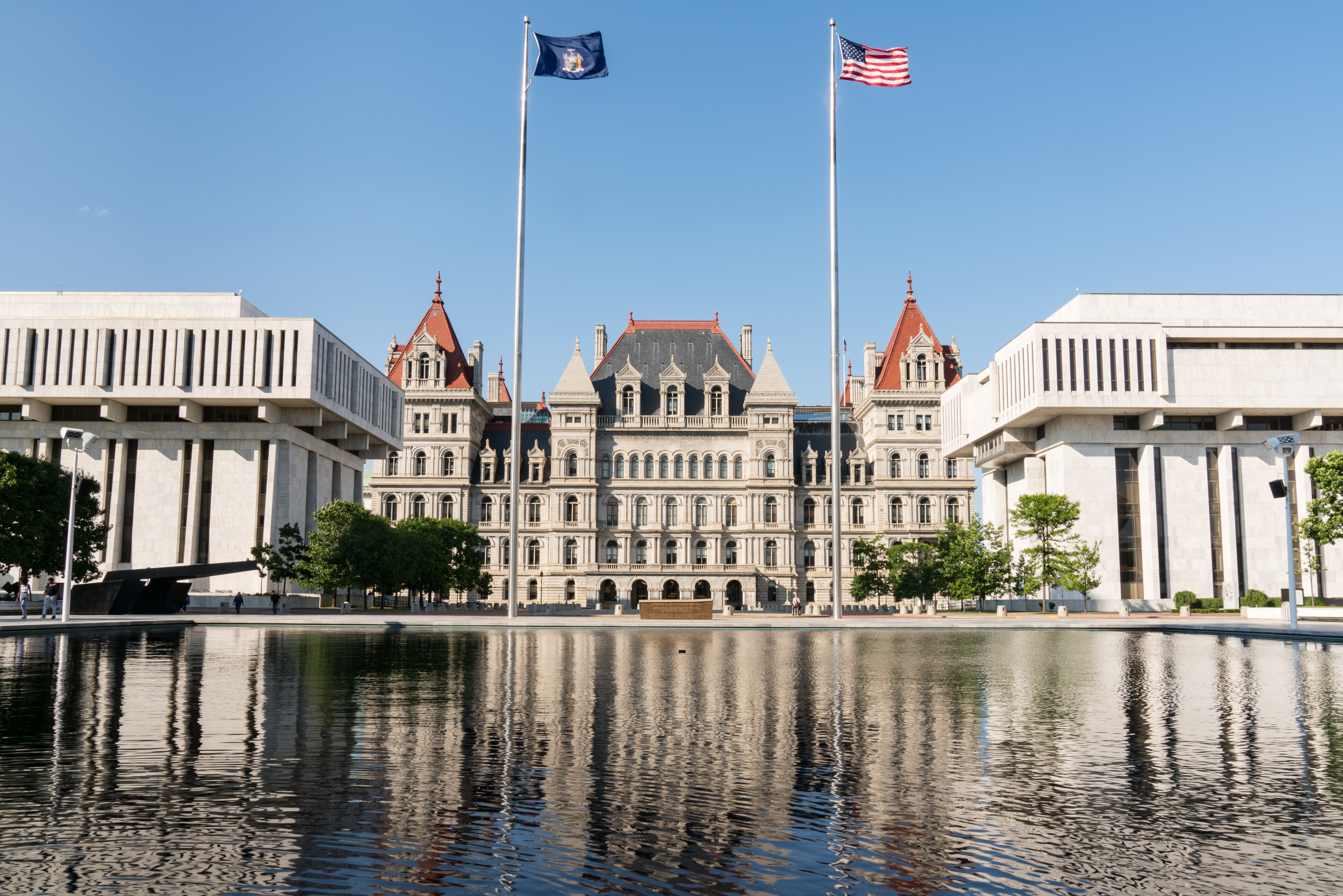 The New York state Capitol building in Albany, framed by two flags on each side.