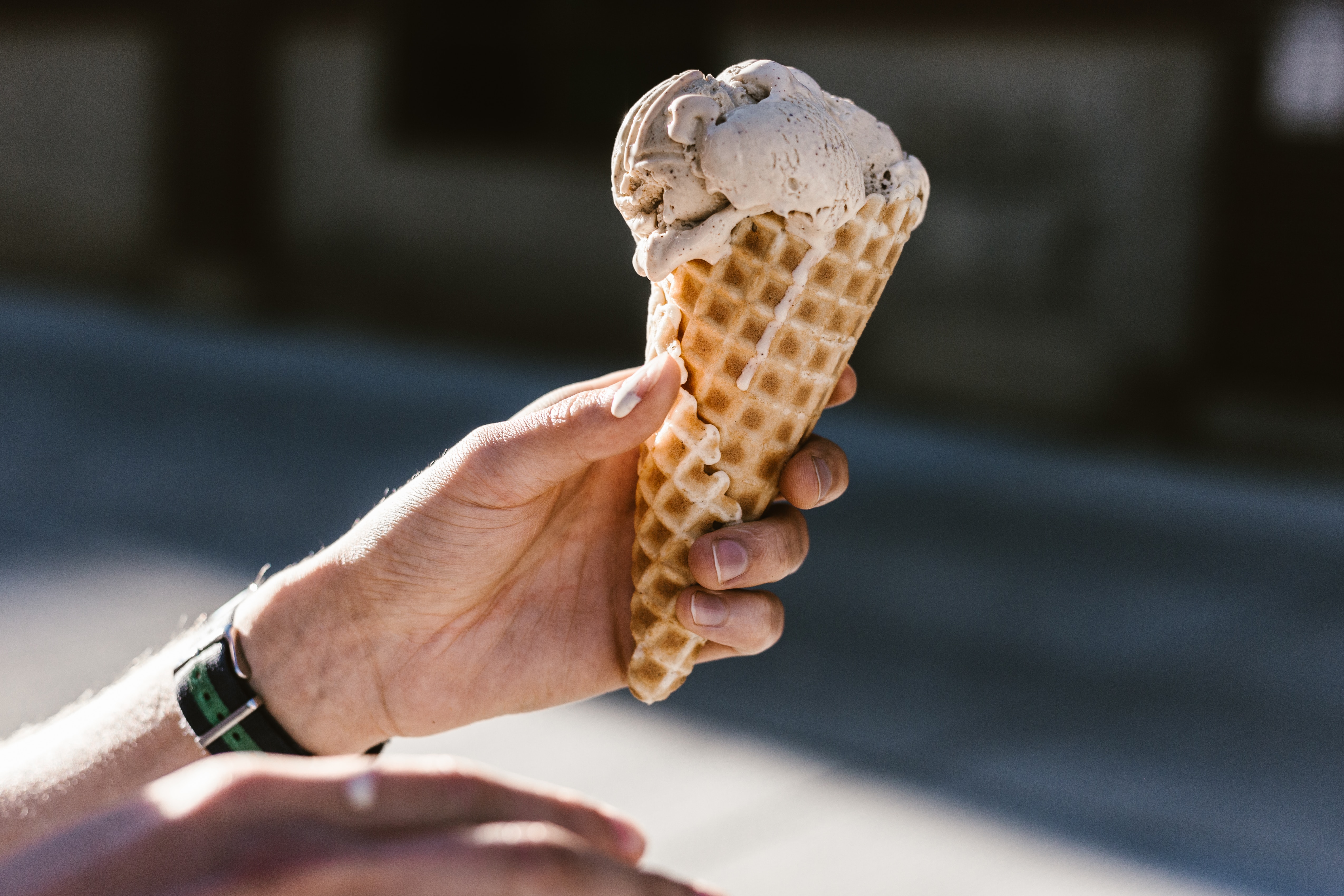 A person holding a melting ice cream cone.