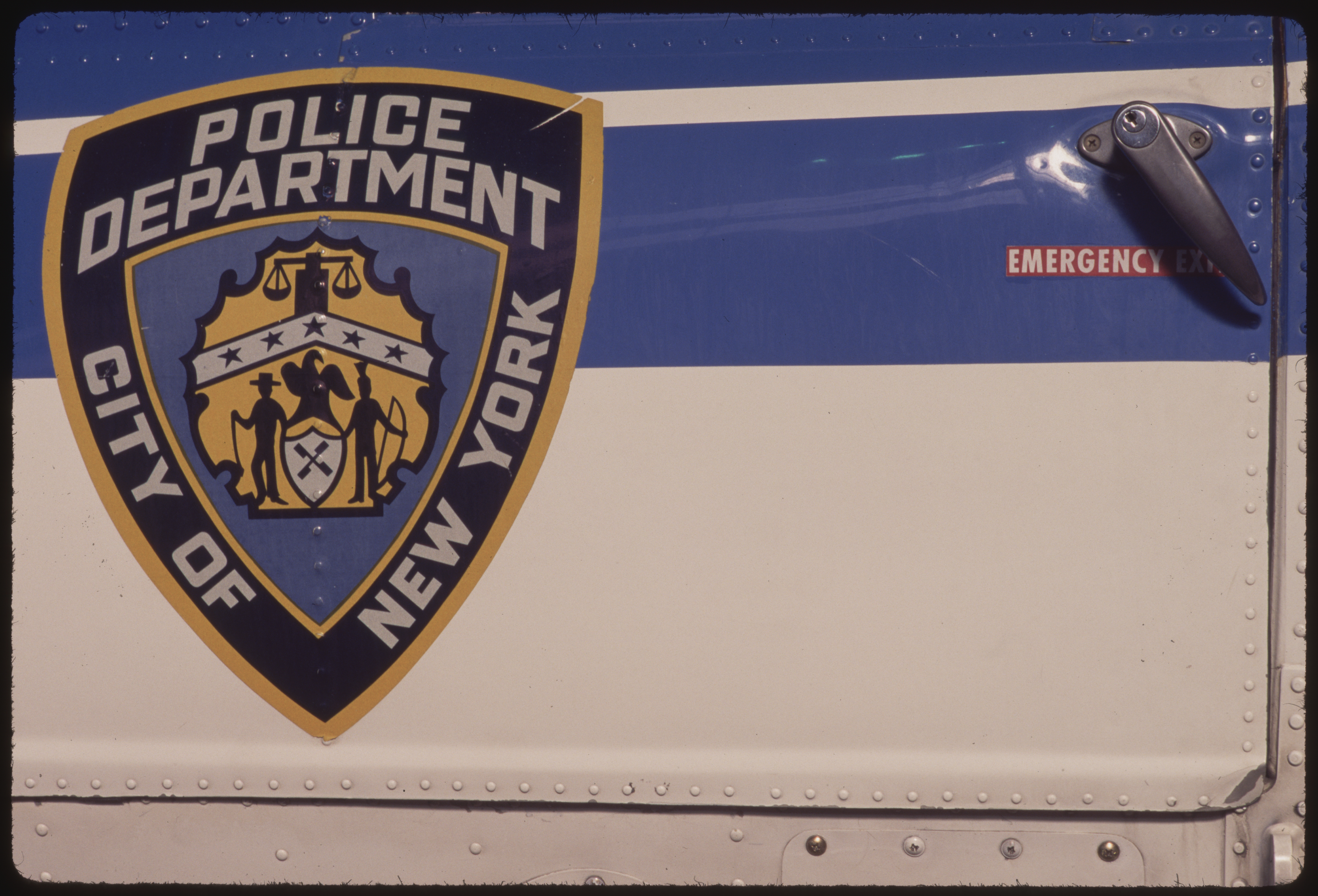 A New York Police Department emblem reading "POLICE DEPARTMENT, CITY OF NEW YORK" is displayed on the side of an NYPD Aviation Unit helicopter in Manhattan.