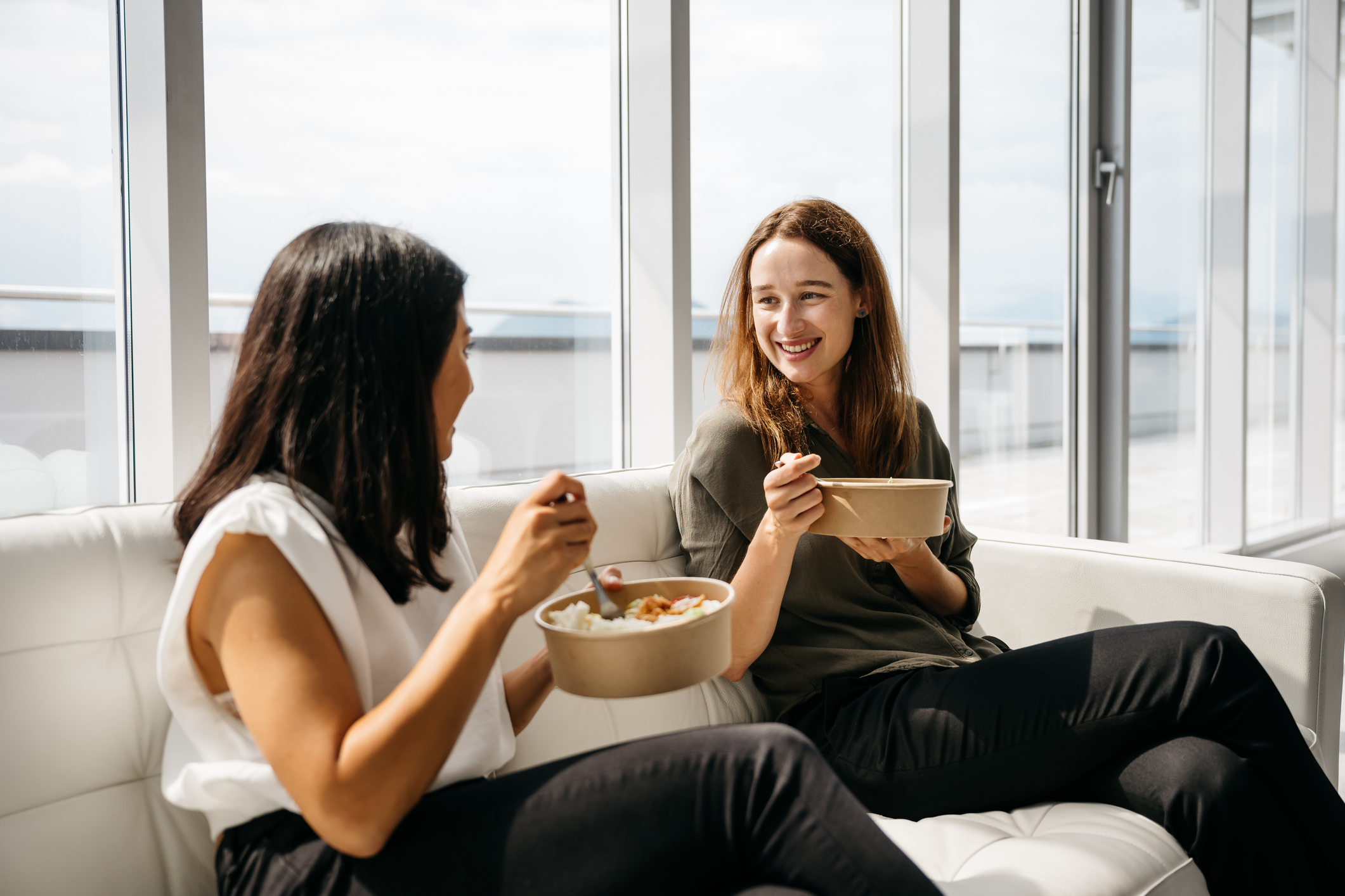 two office workers eating lunch out of bowls
