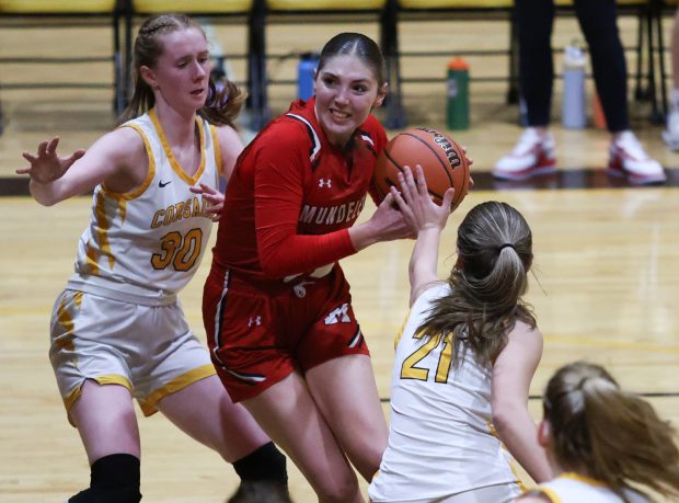 Mundelein guard Rylan Foster (23) attempts to drive into the paint past Carmel's Keira Ackerson (30) and Carmel's Maron Bowes (21) during the Class 4A Carmel Regional semifinal at Carmel Carmel Catholic High School in Mundelein on Monday, Feb. 12, 2024. (Trent Sprague/Chicago Tribune)