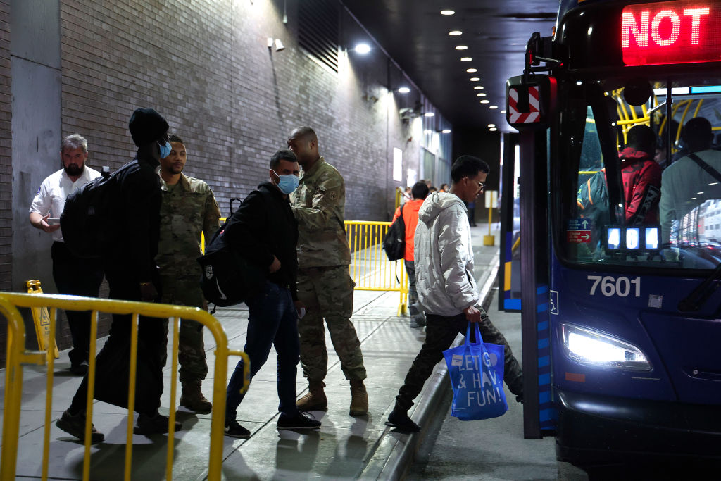 Newcomers board a bus at the Port Authority Bus Terminal.