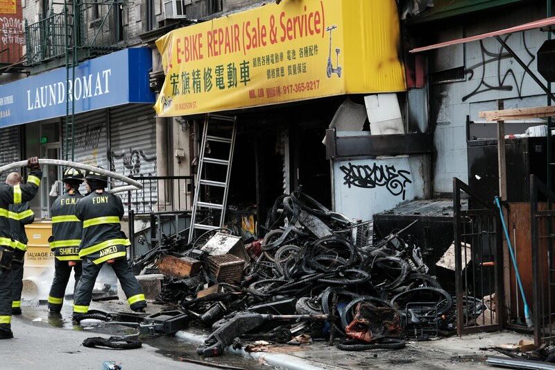 Firefighters work outside a building in Chinatown after four people were killed by a fire in an e-bike repair shop overnight on June 20, 2023.