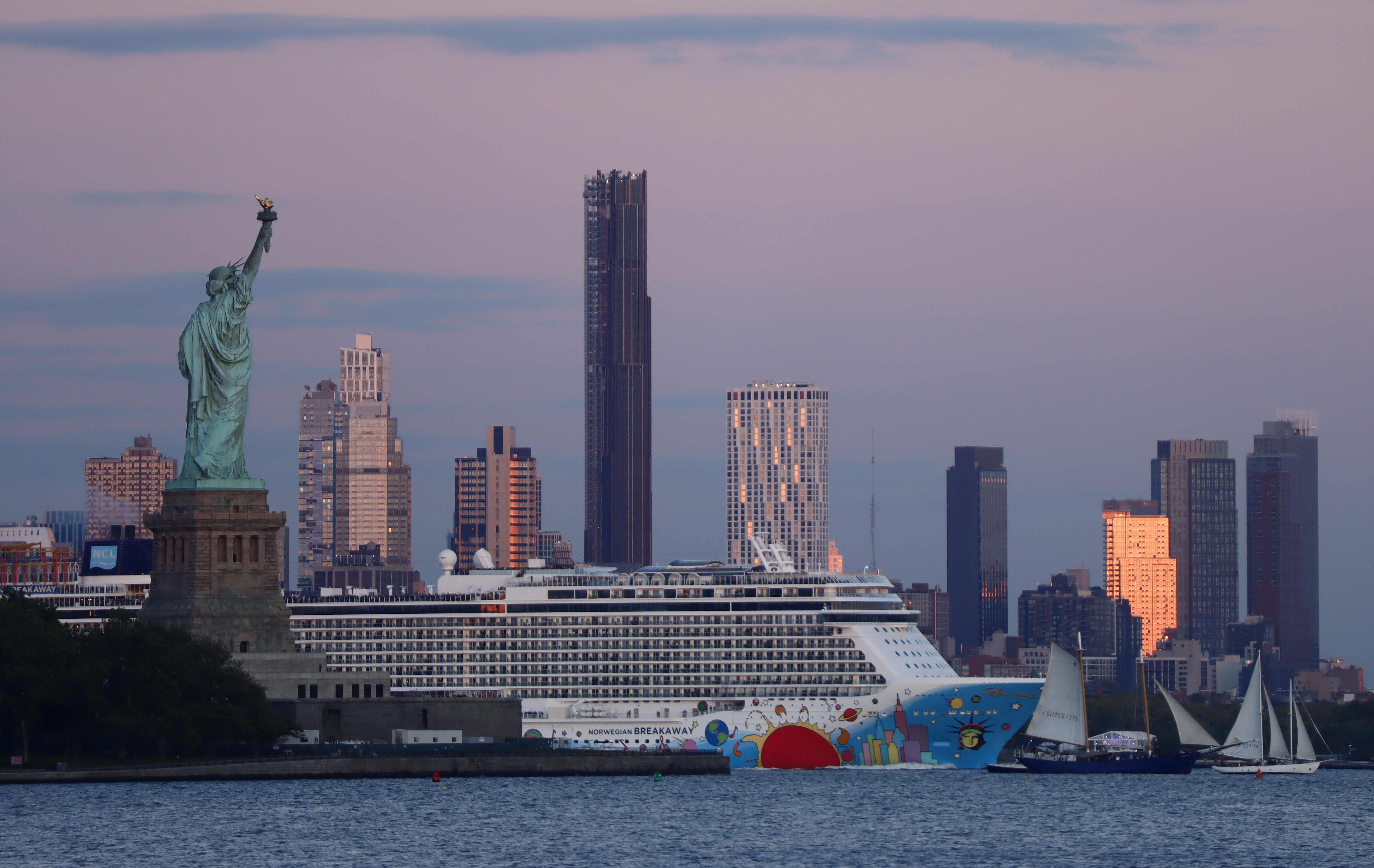 The Norwegian Breakaway cruise ship sails between the Statue of Liberty and the Brooklyn Tower as the sun sets in New York City on Oct. 9, 2022.