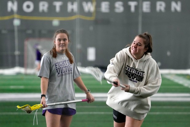 Northwestern's Erin Coykendall, left, watches Izzy Scane shoot as they warm up for lacrosse practice in Evanston, Ill., Tuesday, Feb. 6, 2024. (AP Photo/Nam Y. Huh)