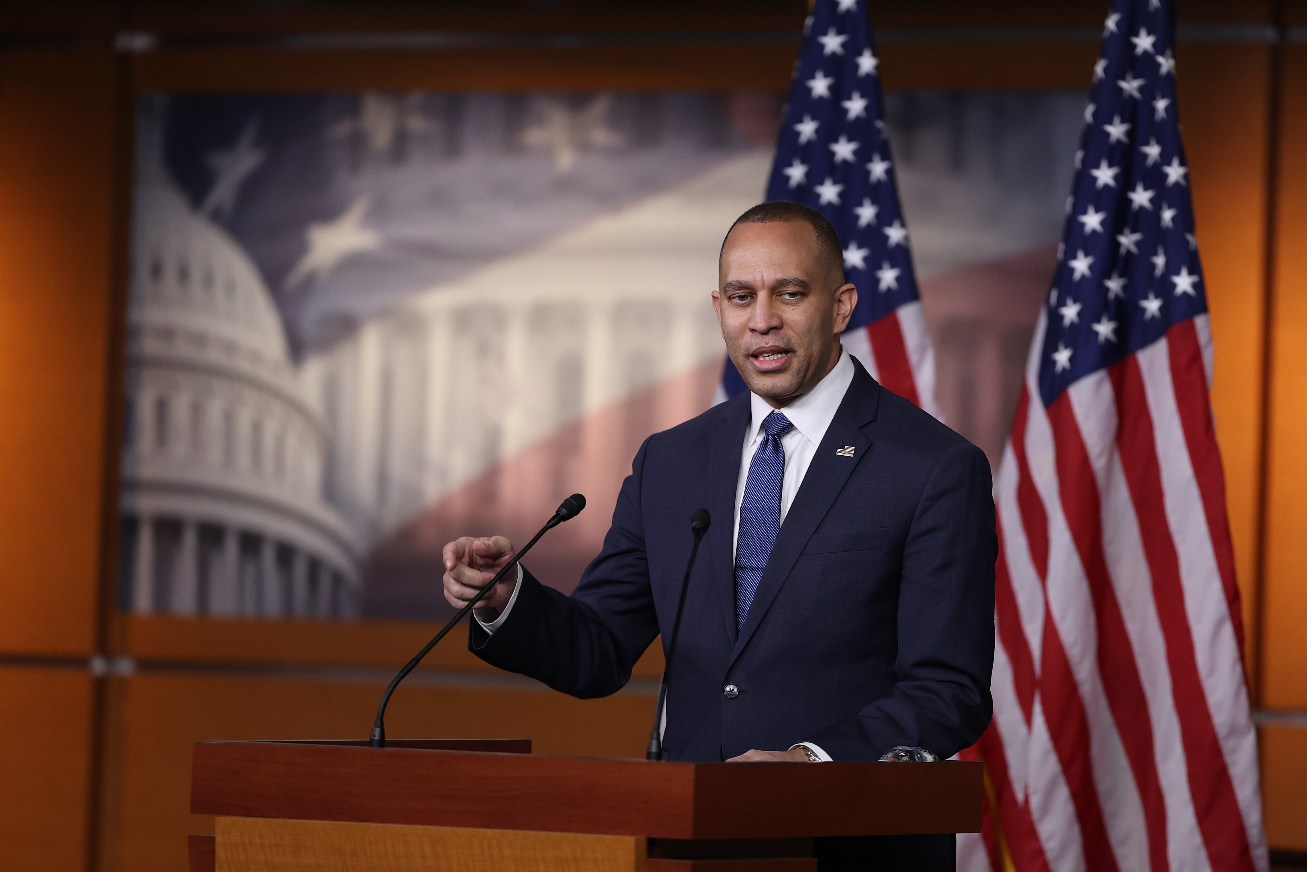 Rep. Hakeem Jeffries stands behind a lectern framed by two American flags.