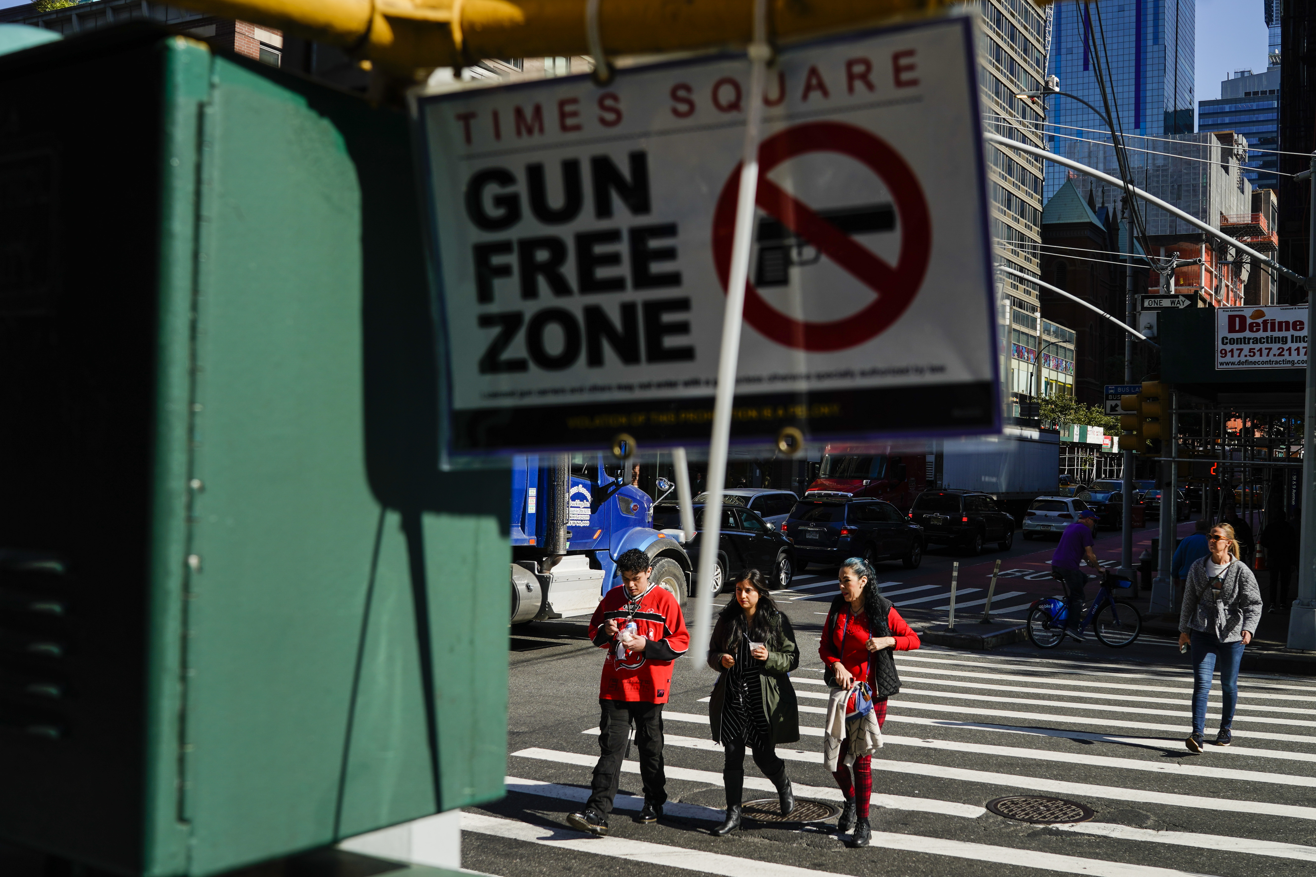 People walk near a Gun Free Zone sign displayed near Times Square on October 11, 2022 in New York City.
