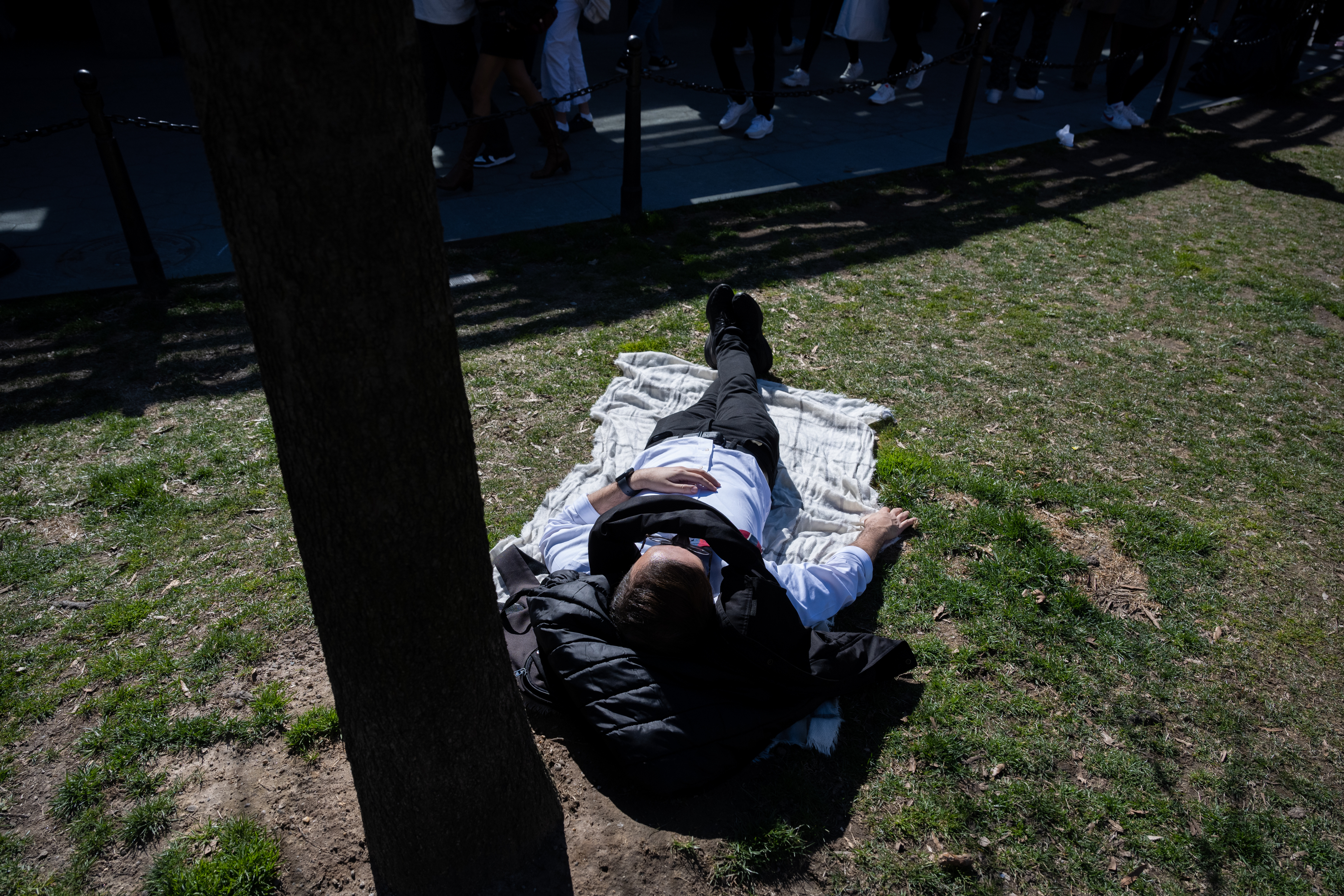 People lie on the grass in Washington Square Park as temperatures reach above 60 degrees during the first weekend of spring on March 26, 2023.