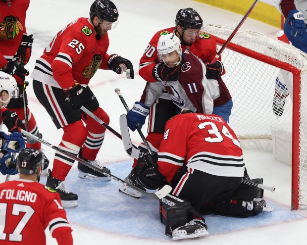 Blackhawks center Tyler Johnson (90) keeps Avalanche center Andrew Cogliano (11) from getting any closer to goaltender Petr Mrázek (34) in the third period on Feb. 29, 2024, at the United Center. (John J. Kim/Chicago Tribune)