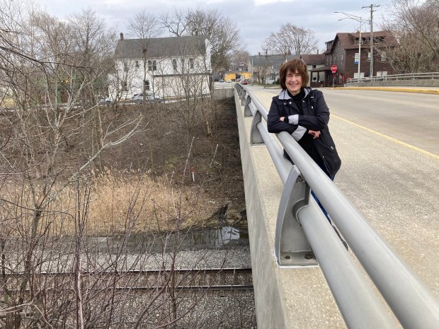 Christina Holston, president of the Monee historical Society stands Feb. 27 on the Main Street bridge in Monee with two of the village's historic buildings in the background. One has been turned into a private residence and the other is being turned into a coffee house. (Paul Eisenberg/Daily Southtown)