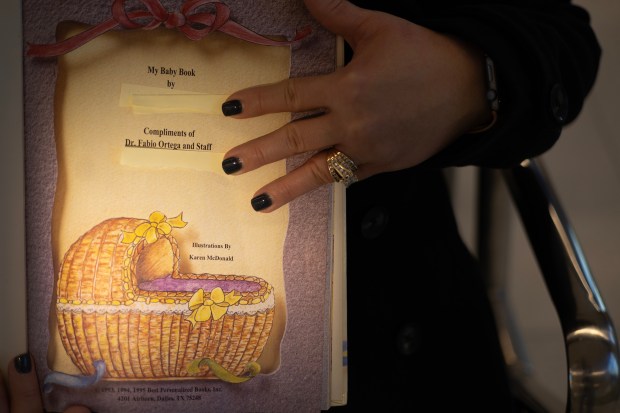 "Elena" holds an unused baby book given to her after Dr. Fabio Ortega helped deliver her first baby more than 20 years ago. She covered her name to protect her privacy. (Stacey Wescott/Chicago Tribune)