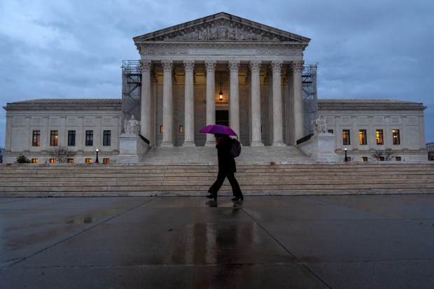 A woman under a purple umbrella walks past the Supreme Court on Feb. 28, 2024, in Washington.(Jacquelyn Martin/AP)