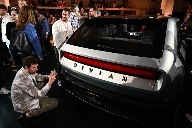 Attendees look at the new Rivian R3 electric vehicle at the Rivian South Coast Theater in Laguna Beach, California, on March 7, 2024. (Patrick T. Fallon/AFP-Getty Images)
