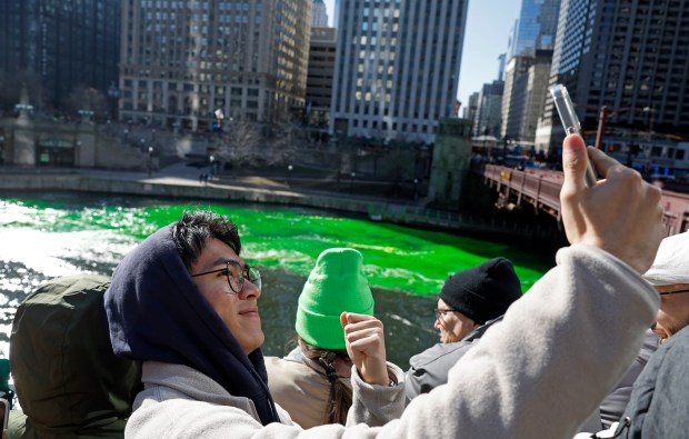 Haomin Zhuang records a selfie as the Chicago River is dyed green by the The Chicago Plumbers Union, Chicago Journeymen Plumbers Local 130, to celebrate St. Patrick's Day, March 16, 2024. (Vincent Alban/Chicago Tribune)