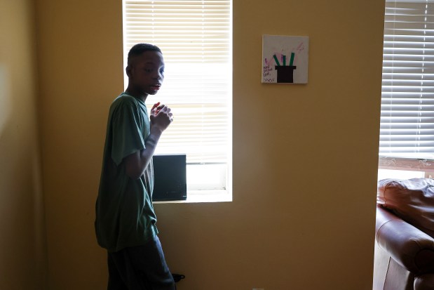 Hezekiah Kelly stands near a craft he completed when he was in school that hangs on the wall in his family's apartment in Highland Park on Wednesday, Dec. 6, 2023. (Eileen T. Meslar/Chicago Tribune)