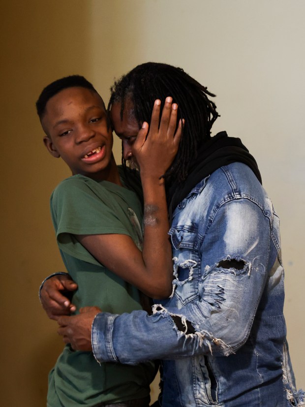 Hezekiah Kelly hugs his father, Fredrick Bass, in the family's apartment in Highland Park on Wednesday, Dec. 6, 2023. (Eileen T. Meslar/Chicago Tribune)