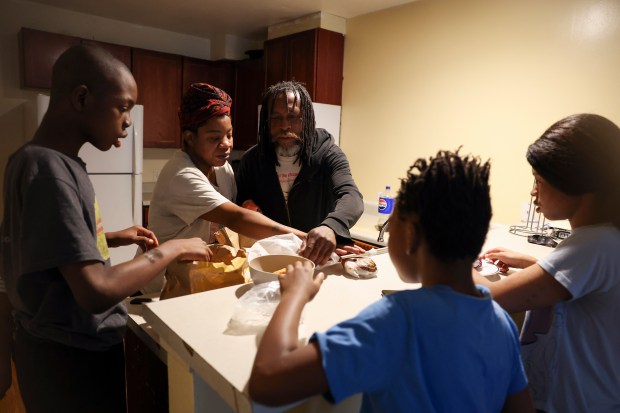 Kiana Kelly, second from left, and her partner, Fredrick Bass, center, sort out food from McDonald's for their children, Hezekiah, from left, Jeremiah and Jakayla, in their apartment in Highland Park on Jan. 3, 2024. (Eileen T. Meslar/Chicago Tribune)