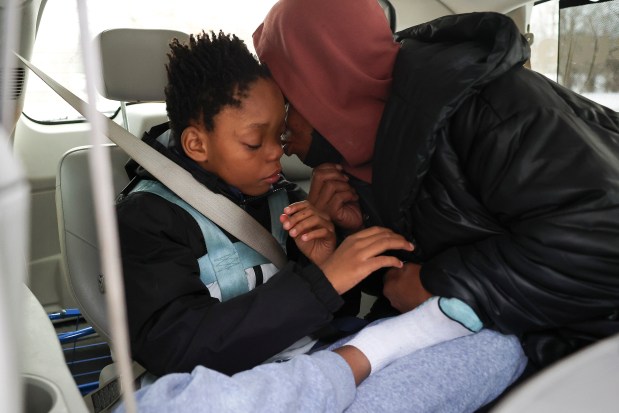 Kiana Kelly kisses her son Jeremiah after she buckled him in his school transport van outside their apartment in Highland Park on Jan. 17, 2024. (Eileen T. Meslar/Chicago Tribune)