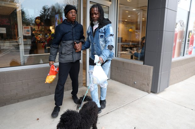 Fredrick Bass, right, leads his son, Hezekiah Kelly, out of the McDonald's near their home in Highland Park on Jan. 3, 2024. (Eileen T. Meslar/Chicago Tribune)