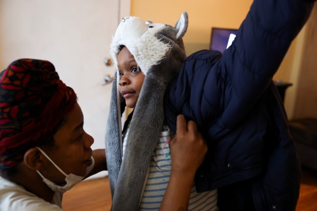 Kiana Kelly helps her daughter, Ke'Asia, put on her coat in their apartment in Highland Park on Wednesday, Jan. 3, 2024. (Eileen T. Meslar/Chicago Tribune)