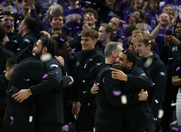 Northwestern guard Brooks Barnhizer (13) hugs guard Boo Buie (0), left, as head coach Chris Collins hugs another player (right) during the Northwestern Men's Basketball NCAA selection show watch party at Welsh-Ryan Arena in Evanston on Sunday, March 17, 2024. (Trent Sprague/Chicago Tribune)