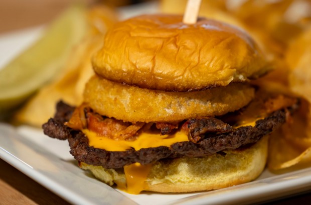 The Smoke House Smash Burger with pulled pork, BBQ sauce, beer cheese sauce and an onion ring available at the ChiSox Bar & Grill as the White Sox preview new food offerings Thursday, March 21, 2024, at Guaranteed Rate Field. (Brian Cassella/Chicago Tribune)