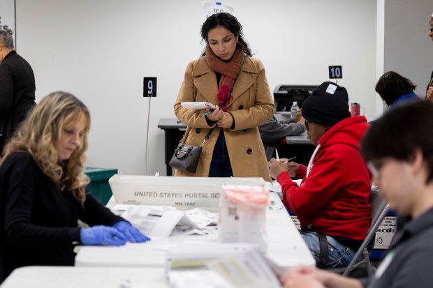 A poll watcher observes as election judges check mail-in ballots before being counted at the central count room on Saturday, March 23, 2024, in Chicago. (Vincent Alban/Chicago Tribune)