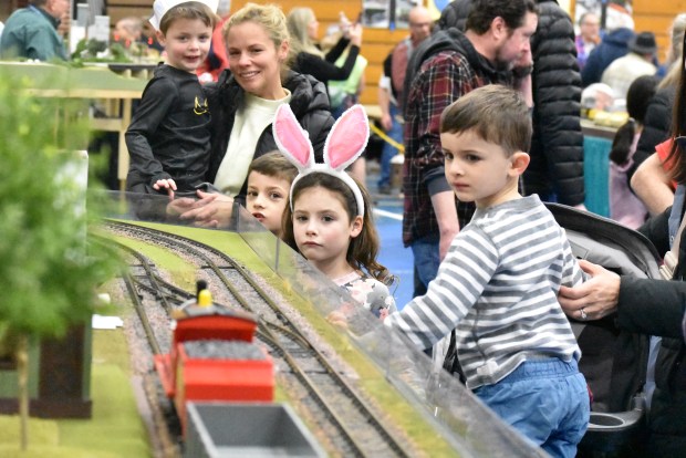 Cameron Thickens, in the bunny ears, watches intently as a model train comes along the bend along with Jack Herrell. (Jesse Wright)