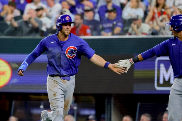 Cubs first baseman Michael Busch, left, gets a hand slap from Yan Gomes after Busch scored in the ninth inning against the Rangers on March 28, 2024, in Arlington, Texas. (Gareth Patterson/AP)