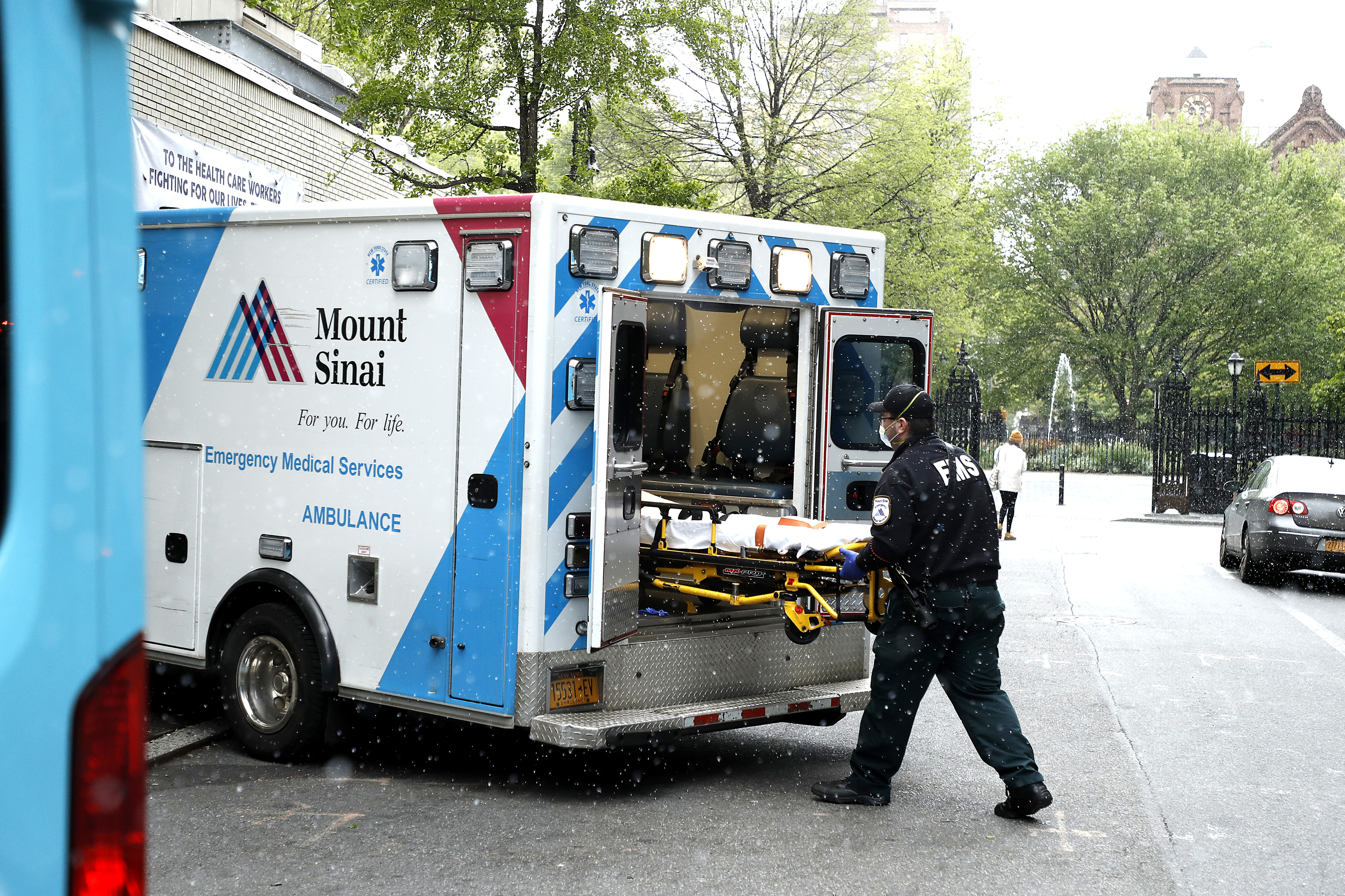 Emergency medical technicians move a gurney outside of a hospital