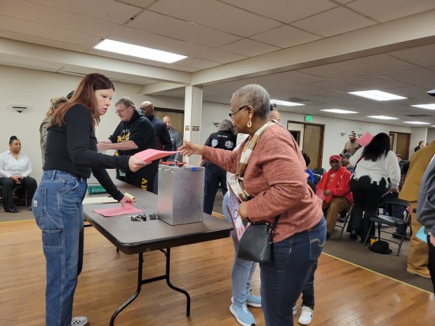 Lake County Democratic Party Administrative Assistant Beth Giles (left) hands Gary Precinct Committeewoman Linda Barbee a ballot for the second round of voting during a caucus to replace Lake County 2nd District Councilman Clorius Lay on March 9. (Michelle L. Quinn/Post-Tribune)