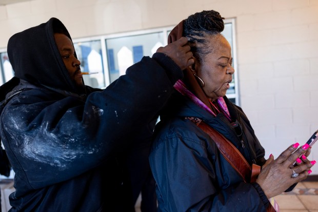 Michael Burns, left, adjusts the jacket of his mother, Carla Johnson, a formerly homeless volunteer with the Chicago Coalition for the Homeless, before they canvass the North Lawndale neighborhood together on Saturday, Feb. 17, 2024. The coalition is urging residents to vote in favor of the "Bring Chicago Home" referendum on the upcoming primary ballot. (Vincent Alban/Chicago Tribune)