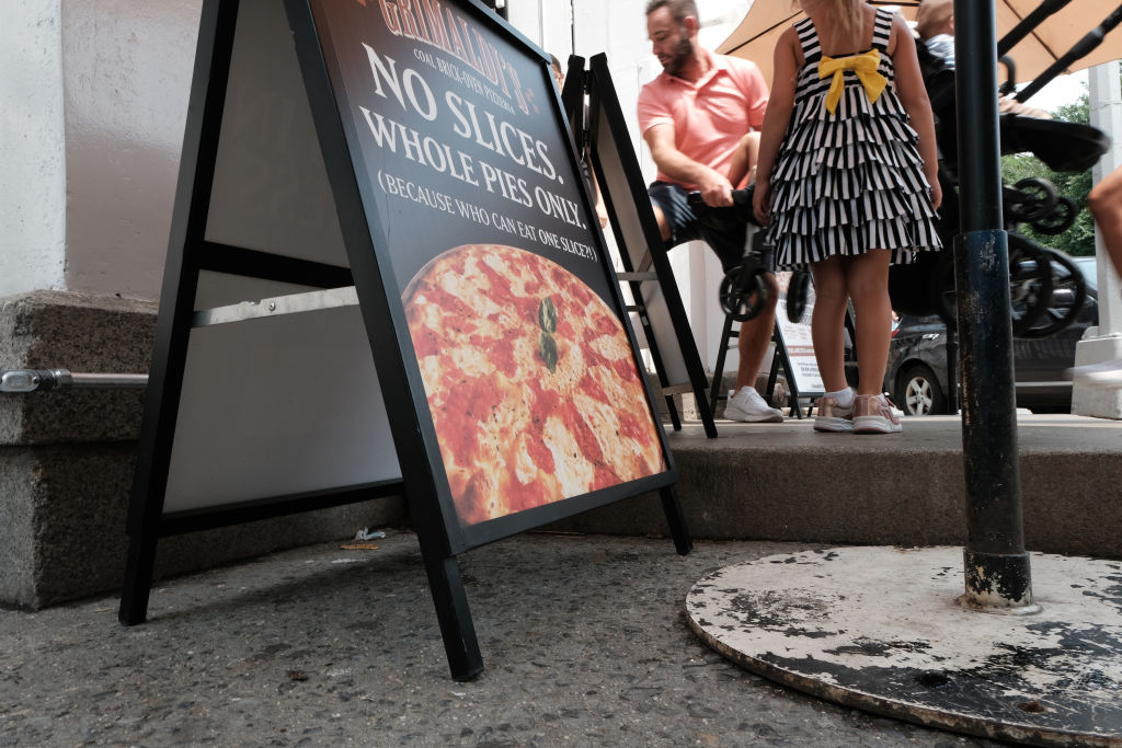 People walk outside Grimaldi Pizzeria's Brooklyn location on June 26, 2023.