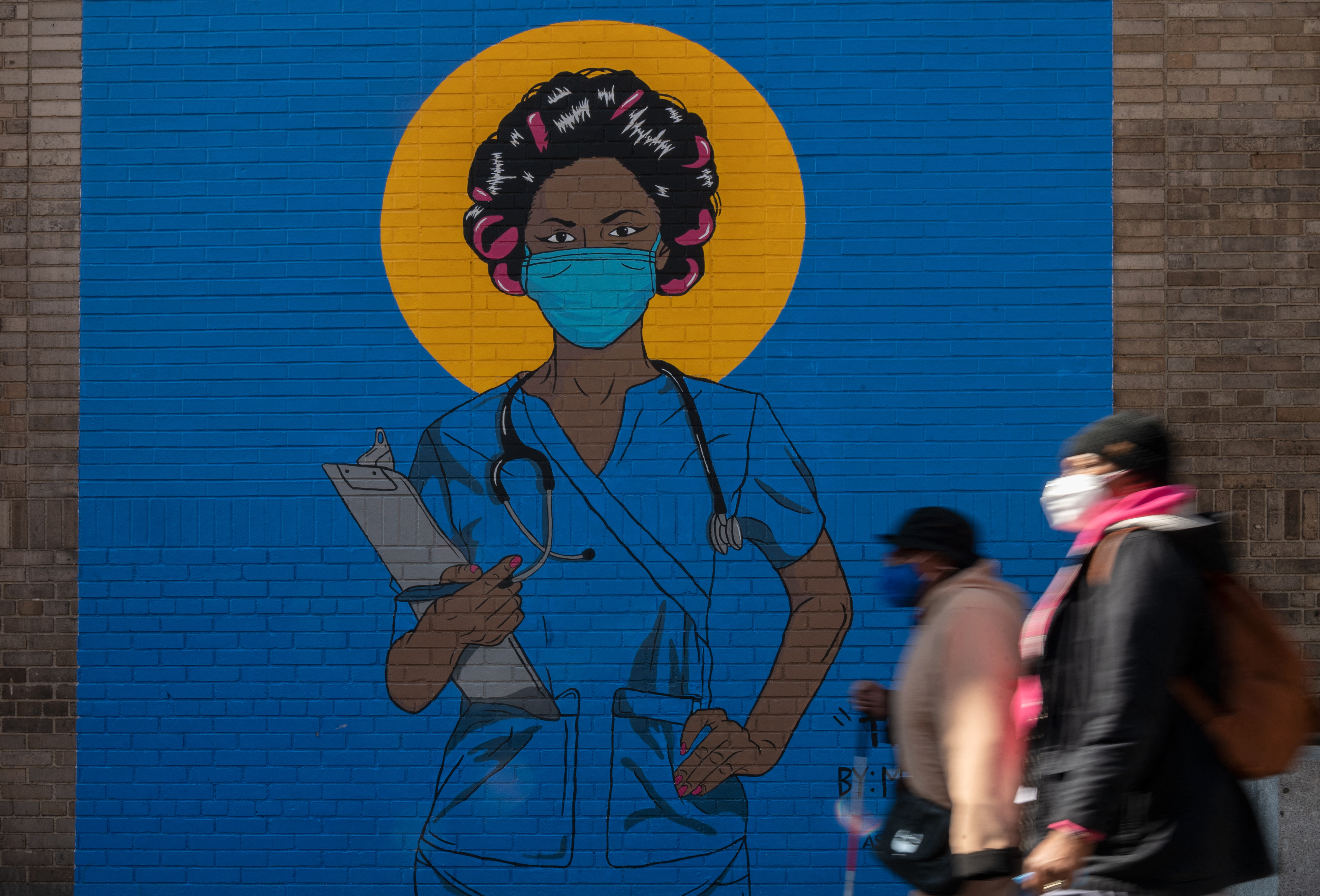 A mural showing a woman dressed in medical scrubs and wearing a mask.