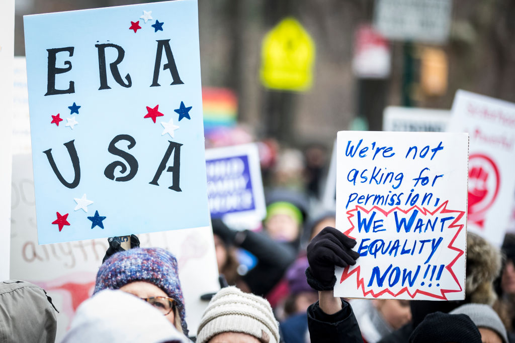 Demonstrators hold signs saying "ERA USA" and a sign asking for "equality now"