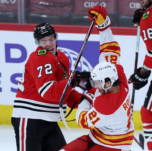 Chicago Blackhawks defenseman Alex Vlasic (72) and Calgary Flames center Kevin Rooney (21) battle in the second period of a game at the United Center in Chicago on March 26, 2024. (Chris Sweda/Chicago Tribune)