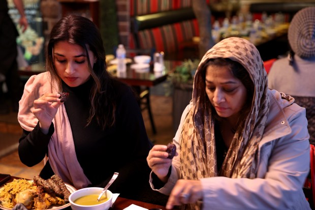 Nubaira Kabir, left, and her mother Nilufar Kabir prepare to bite into dates at 6:59 p.m. to break the daily fast at Al Bawadi Grill in Bridgeview during the Iftar while celebrating Ramadan on Friday, March 15, 2024. (Chris Sweda/Chicago Tribune)