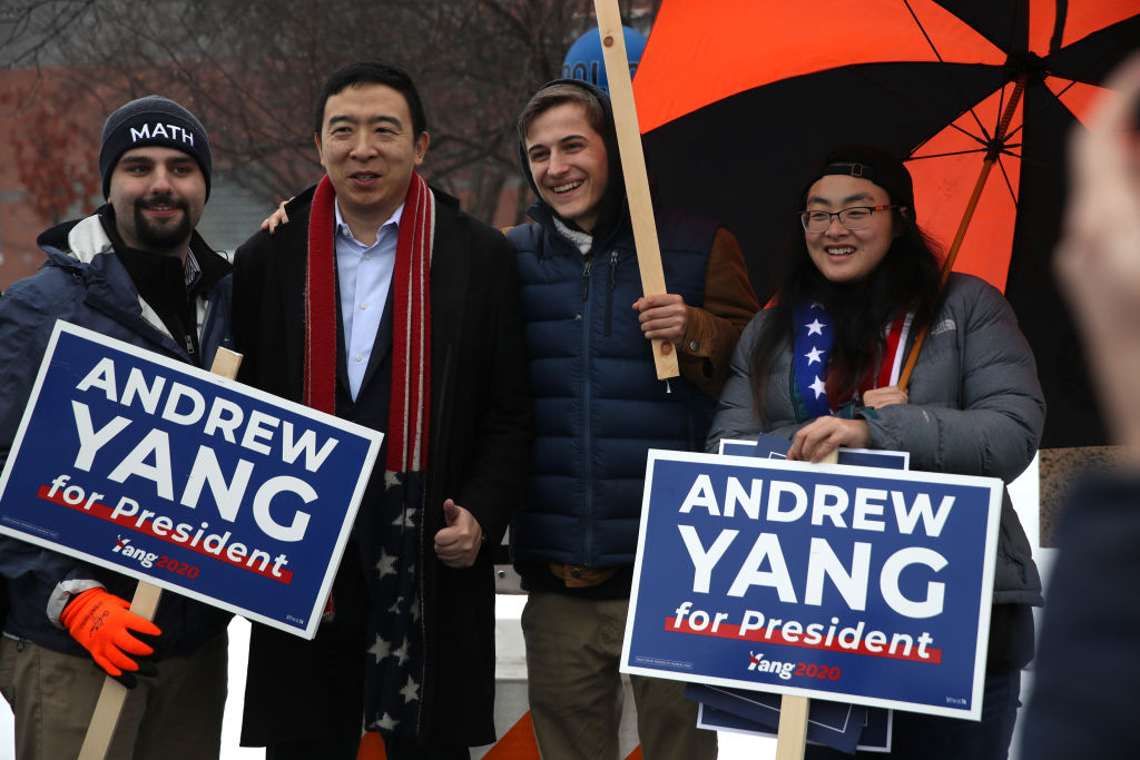 Then-presidential candidate Andrew Yang stands with supporters holding campaign signs in New Hampshire.