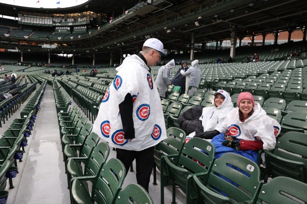 L to R: Skyler Heys (cq), Tricia Severin (cq), and Rhiannon Severin (cq), all of Vancouver, Washington, wait in their seats in cold and wet conditions before a scheduled game between the Chicago Cubs and the Colorado Rockies at Wrigley Field in Chicago on Wednesday, April 3, 2024. (Chris Sweda/Chicago Tribune)