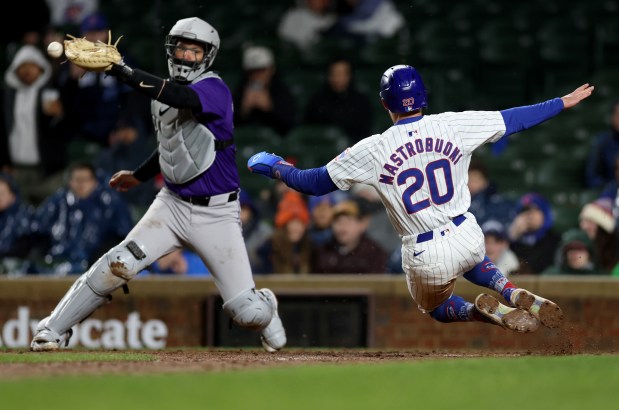Chicago Cubs base runner Miles Mastrobuoni (20) slides in safely at home plate as Colorado Rockies catcher Jacob Stallings is unable to make a play in time on the go-ahead single by Seiya Suzuki in the 8th inning of a game at Wrigley Field in Chicago on Wednesday, April 3, 2024. (Chris Sweda/Chicago Tribune)
