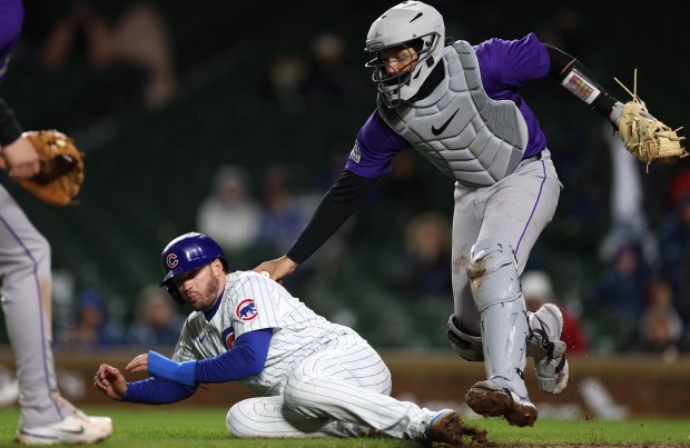 Colorado Rockies catcher Jacob Stallings (25) tags out Chicago Cubs left fielder Ian Happ as Happ is caught in a rundown between third base and home plate in the 8th inning of a game at Wrigley Field in Chicago on Wednesday, April 3, 2024. (Chris Sweda/Chicago Tribune)