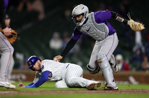 Colorado Rockies catcher Jacob Stallings (25) tags out Chicago Cubs left fielder Ian Happ as Happ is caught in a rundown between third base and home plate in the 8th inning of a game at Wrigley Field in Chicago on Wednesday, April 3, 2024. (Chris Sweda/Chicago Tribune)