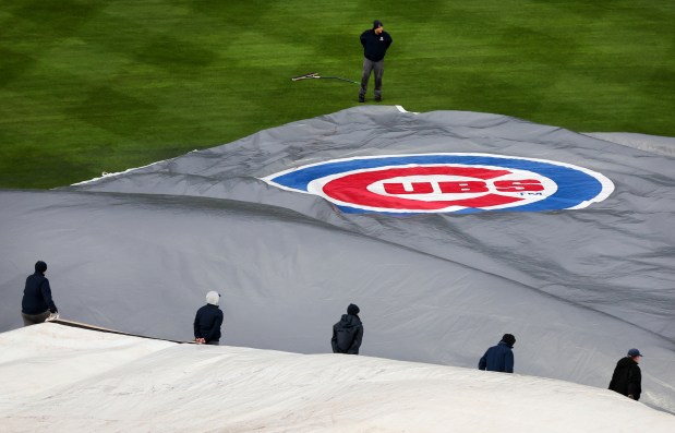 The Wrigley Field grounds crew takes the tarp off the field before a scheduled game between the Chicago Cubs and the Colorado Rockies on Wednesday, April 3, 2024. (Chris Sweda/Chicago Tribune)