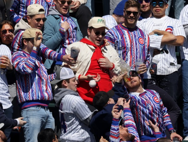 Fans reach for a tossed ball to the bleachers before a game between the Cubs and Dodgers on April 6, 2024, at Wrigley Field. (John J. Kim/Chicago Tribune)