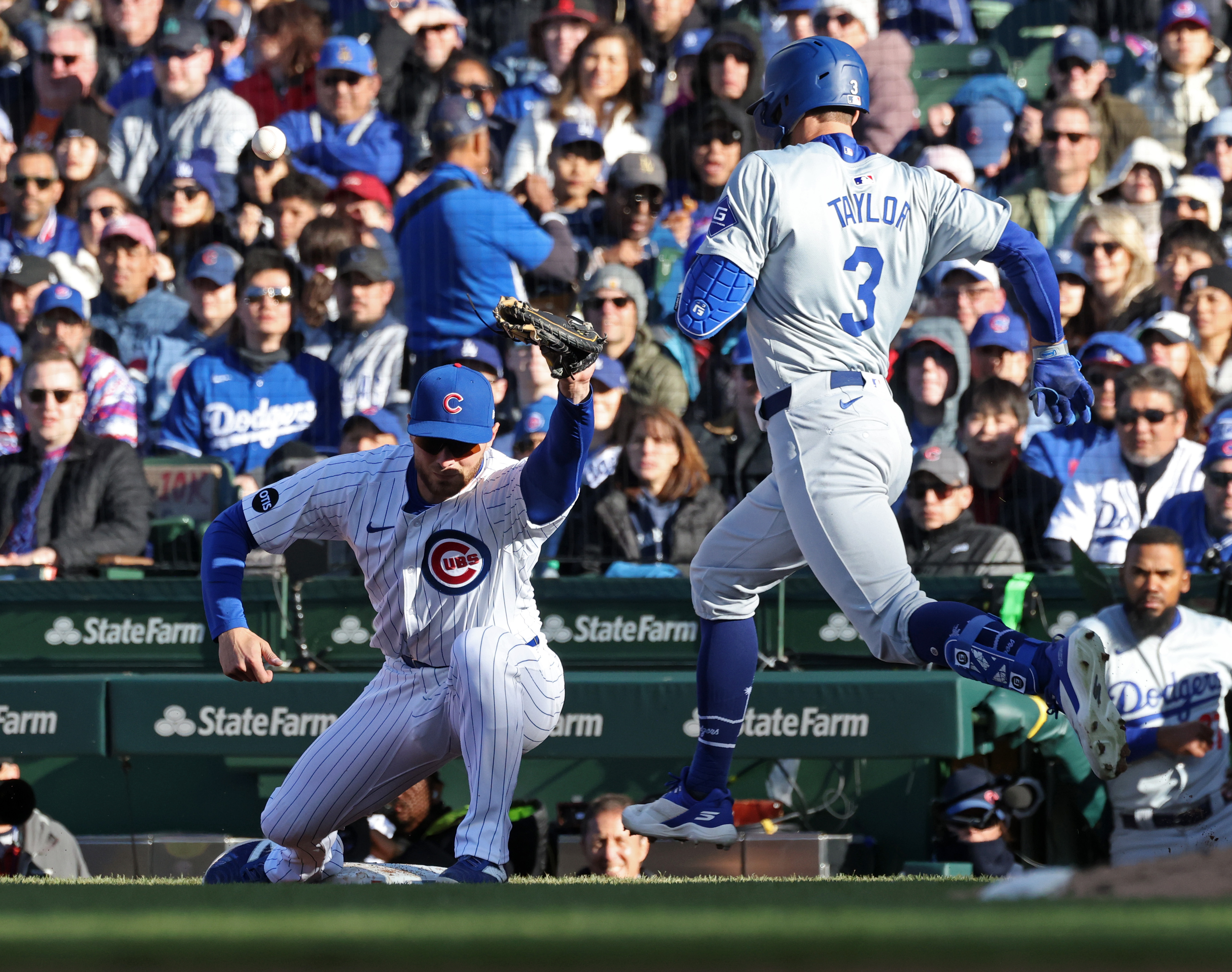 Dodgers left fielder Chris Taylor (3) crosses first base safely on a throwing error as Cubs first baseman Michael Busch (29) fields the throw in the eighth inning at Wrigley Field on April 6, 2024, in Chicago. (John J. Kim/Chicago Tribune)