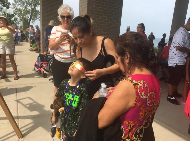 Evelyn Constanza, 33, of Chicago helps her son, Danny Guerrero, 7, watch his first solar eclipse on August 21, 2017 at the Portage Lakefront Park.