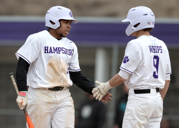 Hampshire's Wilson Wemhoff (21) and Jack Perrone (9) slap hands after Wemhoff scored a run in the third inning during a non-conference game against Woodstock North on Thursday, April, 11, 2024 in Hampshire. Hampshire won, 15-0 in four innings.H. Rick Bamman / For the Beacon News