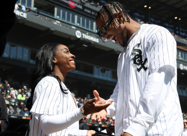 Gymnast Simone Biles and new Chicago Bears safety Jonathan Owens laugh after Owens throws out a ceremonial first pitch before a game between the White Sox and Reds at Guaranteed Rate Field on April 13, 2024, in Chicago. (John J. Kim/Chicago Tribune)